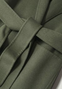 Olive green fabric belt with a soft, textured finish, featuring a large knot and overlapping sections for a secure fit.