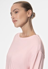 Maglietta in cotone rosa chiaro con scollatura a giro e spalle abbassate, caratterizzata da una texture morbida e una vestibilità comoda.