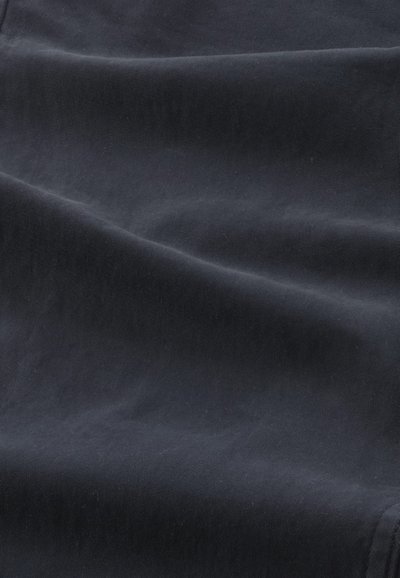 Tissu noir avec de subtils plis diagonaux et une texture douce et lisse.