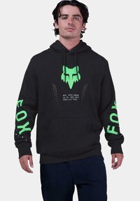 Sudadera negra con un gráfico de un zorro verde en el frente, texto verde en las mangas y acentos de puntos. Hecha de una tela suave con un bolsillo en la parte frontal.