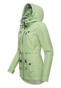 Giacca impermeabile verde chiaro con cappuccio, vita regolabile con coulisse e dettagli neri. L'interno presenta una fodera a motivo foglia.