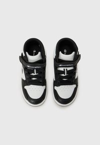 Baskets montantes noir et blanc avec lacets et bande Velcro, arborant un logo Champion sur le côté. Présentées sur un fond uni.