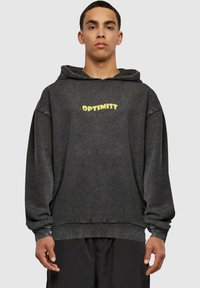 Felpa nera con una vestibilità comoda, caratterizzata dalla parola "OPTIMIST" in giallo sul davanti. Realizzata in un tessuto testurizzato con cappuccio regolabile.