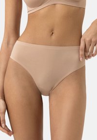Beige saumaton kangas hipster alusvaatteet, joissa on sileä rakenne, keskikorkea malli ja minimalistinen vyötärönauha. Ei näkyviä saumoja tai kuvioita.