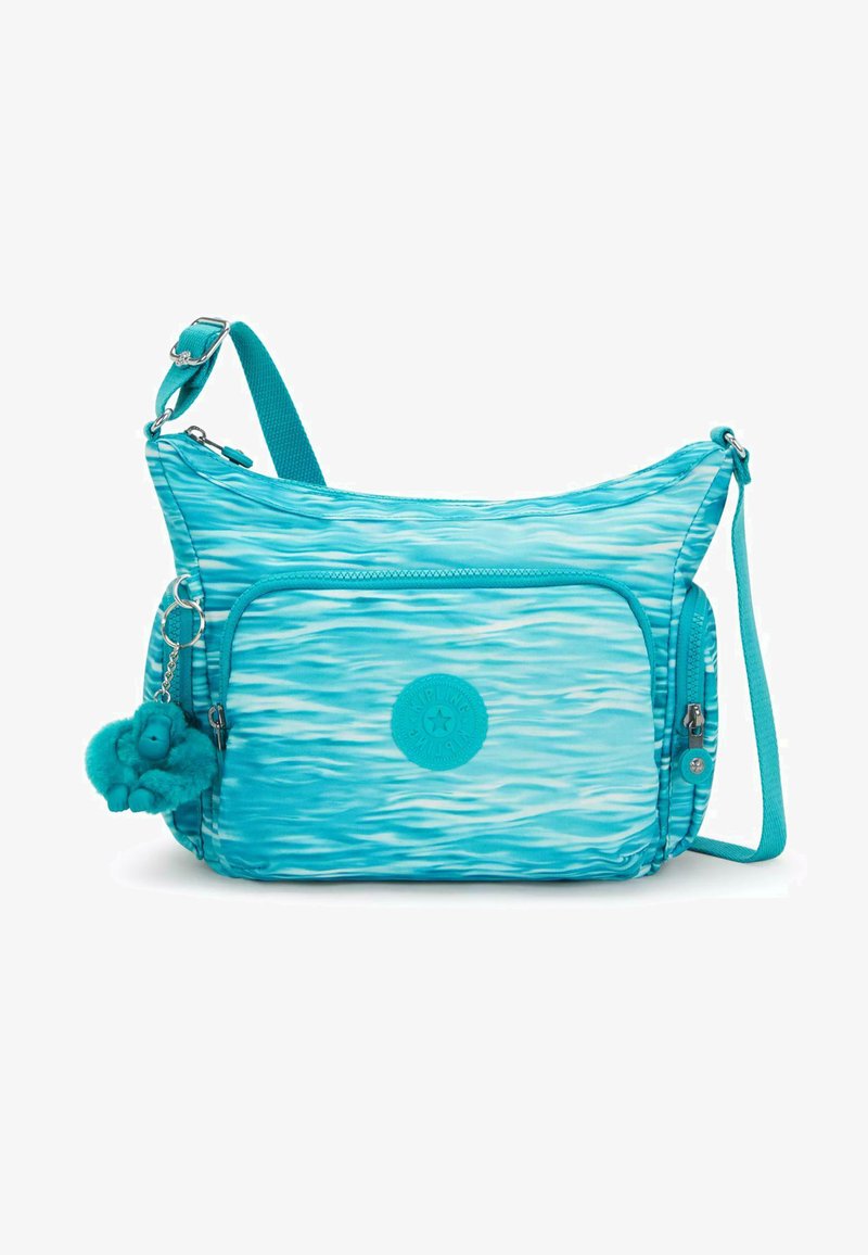 Turkis skuldertaske med bølgemønstre, lavet af holdbart stof. Har en frontlomme med lynlås, en nøglering charm og en justerbar rem.
