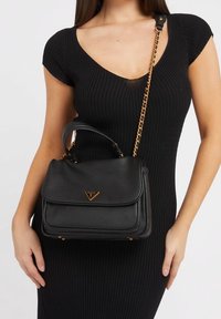 Czarna skórzana torebka o teksturowym wykończeniu, ze złotymi akcentami i odpinanym łańcuszkiem. Posiada projekt z klapką.