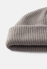 Grå strikket lue med ribbestruktur, som har en rullet mansjett og mykt, ull-lignende materiale. Enkel og minimalistisk design.
