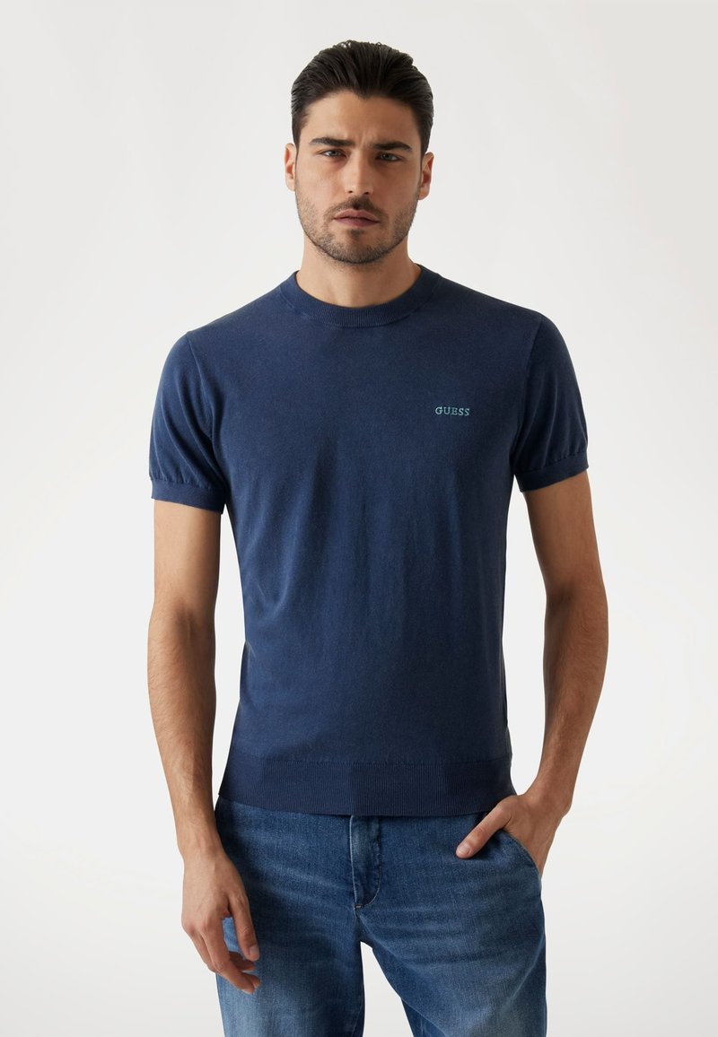 T-shirt blu navy a maniche corte in tessuto morbido, con scollatura a girocollo e un logo sottile in verde sull'area sinistra del torace.