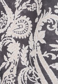 Zwarte stof met ingewikkelde witte bloemen- en paisleypatronen, met krullen en bladeren, wat een gedetailleerde textuur geeft.