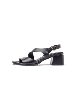 Black leather sandal with open toe, crisscross straps, adjustable ankle strap with gold buckle, and block mid heel.