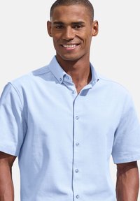 Svetlomodrá košeľa s krátkym rukávom a gombíkmi s textúrovanou tkaninou, klasickým golierom a prednými gombíkmi. Hladký a ľahký vzhľad.
