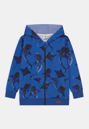 Sudadera con capucha y cremallera azul, con un patrón de mantarrayas azul oscuro con detalles moteados. Incluye un bolsillo delantero y puños acanalados.