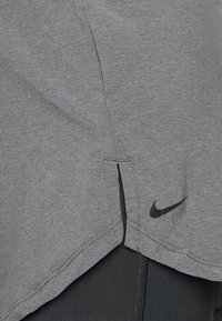 Grå idrottströja med en lätt fållsplits. Tillverkad av mjukt material, har Nike-logotypen i svart nära nedre högra hörnet.