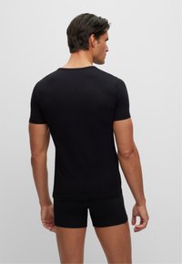 Schwarzes T-Shirt mit kurzen Ärmeln aus glattem Stoff, taillierte Passform, mit einem schlichten Rundhalsausschnitt und sauberem Finish am Saum und an den Ärmeln.