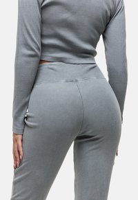 Grijs geribbeld loungewear-set bestaande uit een aansluitend long-sleeve shirt en hoge taille broek. Zachte textuur met een naadloos ontwerp.