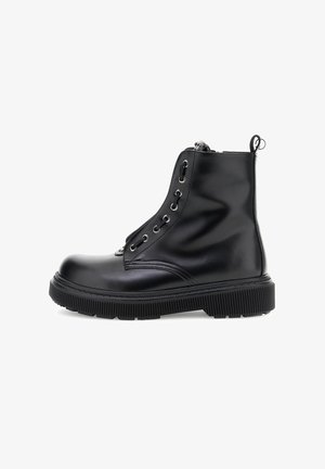 Bottine en cuir noir avec semelle épaisse à crans, fermeture éclair sur le côté, lacets et tirant à l'arrière, présentée en profil sur fond blanc.