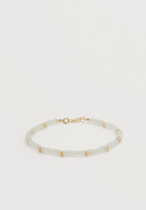 Zartes Armband mit kleinen, durchsichtigen weißen Perlen, getrennt durch goldene Abstandshalter und einem goldenen Verschluss mit verstellbaren Gliedern.