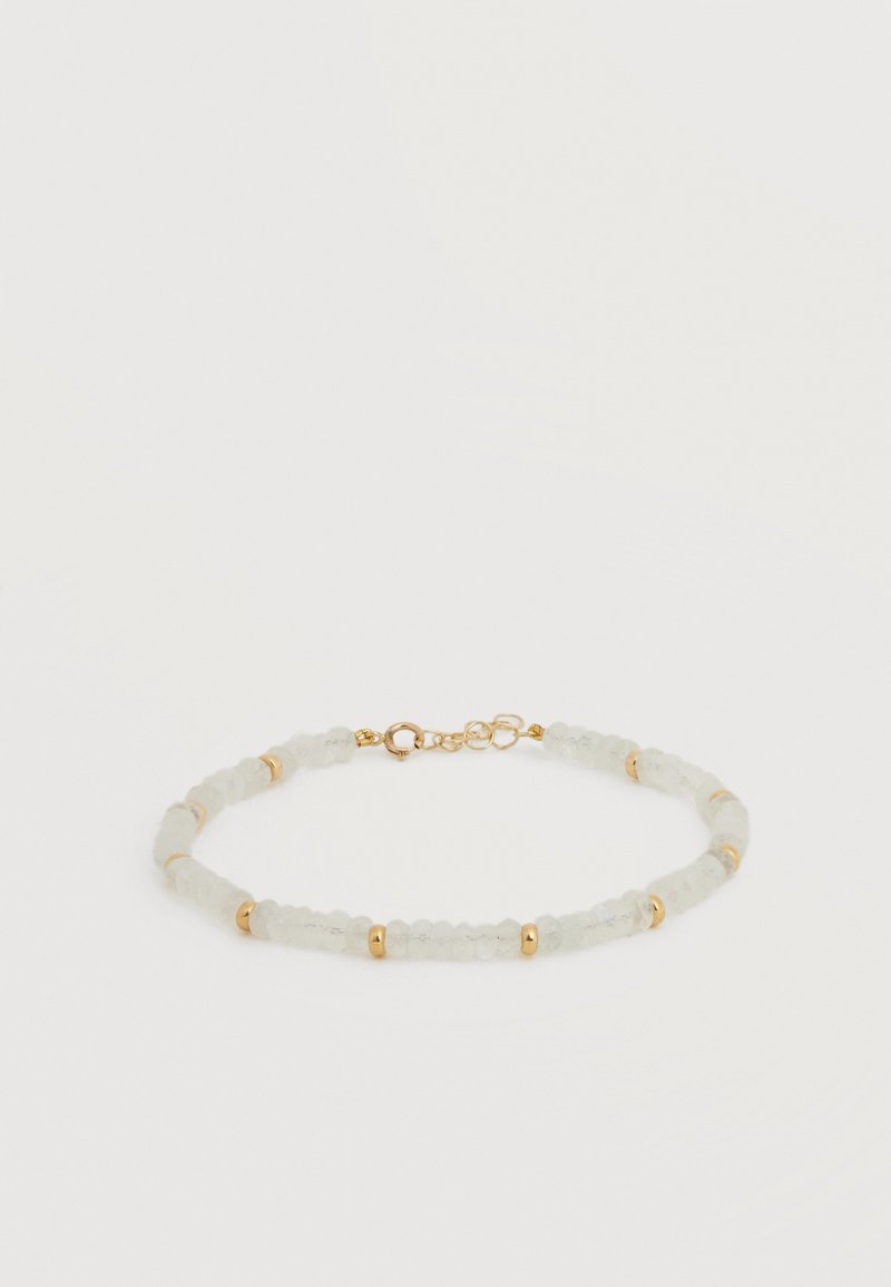 Λεπτό βραχιόλι με μικρές, διάφανες λευκές χάντρες διαχωρισμένες από χρυσά διαχωριστικά και ένα χρυσό κούμπωμα με ρυθμιζόμενες αλυσίδες.