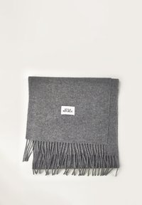 Sciarpa di lana grigia con bordi frangiati, di forma rettangolare e con un piccolo etichetta con "STYLE REPUBLIC" al centro in alto.