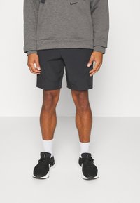 Sudadera gris de Nike combinada con pantalones cortos negros. El atuendo presenta un diseño sencillo, una tela suave y zapatillas deportivas negras con acentos blancos.