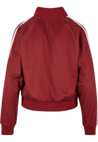 Červená síťovaná bunda s žebrovaným límcem, elastickými manžetami a lemem. Po stranách bílé pruhy a texturovaný materiál po celé zadní části.