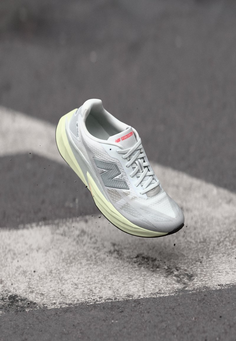 Lightweight running shoe with a white mesh upper, yellow midsole, and gray accents. Features a prominent ‘N’ logo and textured surface.