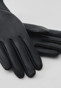 Schwarze Lederhandschuhe mit glatter Textur, mit tailliertem Design und deutlichen Nähten für jeden Finger. Weicher, minimalistischer Stil.