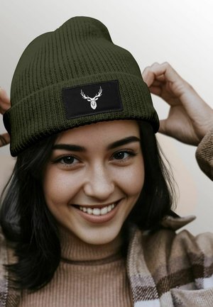 Olive green knitted beanie with a textured design and a black patch featuring a deer graphic. Soft material and fold-over cuff.