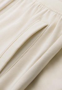 Cremfarbene Jogginghose aus strukturiertem Stoff, mit einer Seiten Tasche und einem elastischen Bund für zusätzlichen Komfort.