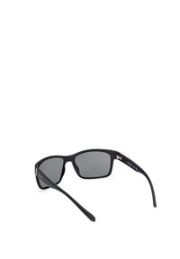 Gafas de sol negras con un acabado mate, grandes lentes grises, montura ligeramente curva y brazos esbeltos que presentan un pequeño acento metálico.