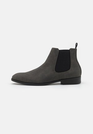 Gray Chelsea boot with a suede upper, elastic side panels, and a contrast black textile insert. Flat rubber sole and streamlined shape.