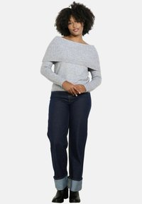 Gray off-the-shoulder sweater with ribbed texture, paired with dark blue high-waisted jeans featuring cuffed hems and black ankle boots.