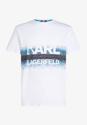 White cotton T-shirt featuring a gradient design with blue and black splatter patterns and bold text reading "KARL LAGERFELD." Short sleeves.