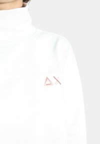 Felpa bianca con collo alto caratterizzata da una trama morbida e un logo geometrico ricamato in rosa sul lato sinistro del petto.