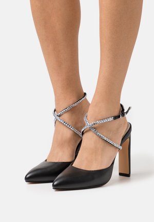 Mustad nahast kontsad terava nina ja jämeda kontsaga. Kaunistuseks on pahkluude ümber ristsuunduvad sädelevad kinked.