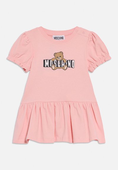 Vestido rosa para niña pequeña con mangas abullonadas, falda fruncida y gráfico de un oso de peluche sosteniendo el texto "MOSCHINO" en el frente.