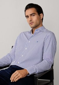 Blau-weißer gestreifter Button-Up-Hemd mit Kragen, gefalteten Manschetten und einem kleinen Logo auf der Brust. Strukturierte Baumwollqualität, taillierte Passform.