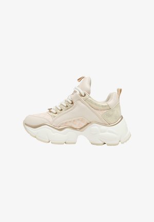 Zapatillas en rosa claro y crema, con una parte superior texturizada, suela gruesa blanca, cordones y detalles metálicos en el talón y la parte superior.