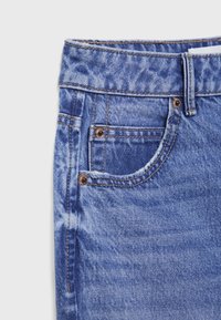 Denim jeans in light blue wash with a faded texture. Features include a waistband, front pockets, and contrasting stitching.