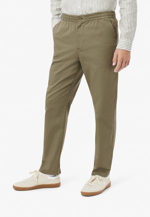 Olive green, lightweight, elastic-waist pants with side pockets. Tailored fit and smooth texture. Paired with cream sneakers.