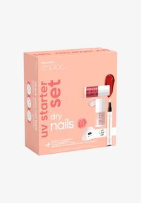 Set de démarrage UV dans une boîte pêche, comprenant du vernis à ongles, un stylo à finition brillante et une lampe LED. Instructions incluses sur le côté.