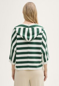 Sweat à capuche rayé vert et blanc avec une coupe ample et des manches trois-quarts. Tissu doux avec un ourlet fendu et un détail de fermeture à l'arrière.
