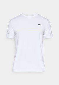 Witte katoen t-shirt met korte mouwen, ronde halslijn, subtiele gele Lacoste branding en een klein groen krokodillenlogo op de borst.