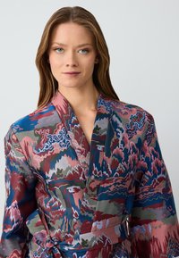 Sukienka kimono z satyny z żywym, abstrakcyjnym wzorem w odcieniach niebieskiego, różowego i zielonego; ma zapięcie owijane i szerokie rękawy.
