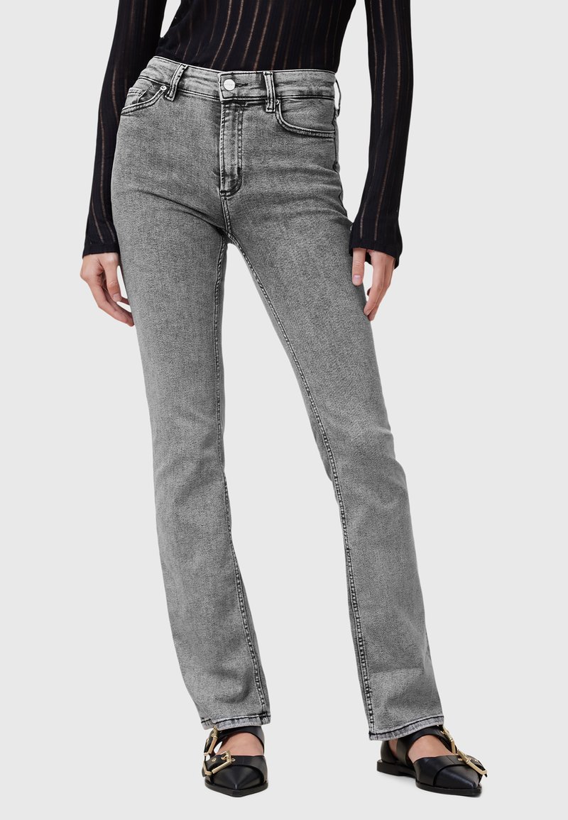 Jeans grigi alti in vita con vestibilità dritta, caratterizzati da cuciture visibili e design a cinque tasche, abbinati a scarpe basse nere.