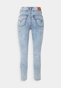 Jeans skinny in denim azzurro chiaro con vita alta, dotati di un'etichetta del marchio marrone, cuciture posteriori sottili e design classico della tasca posteriore.