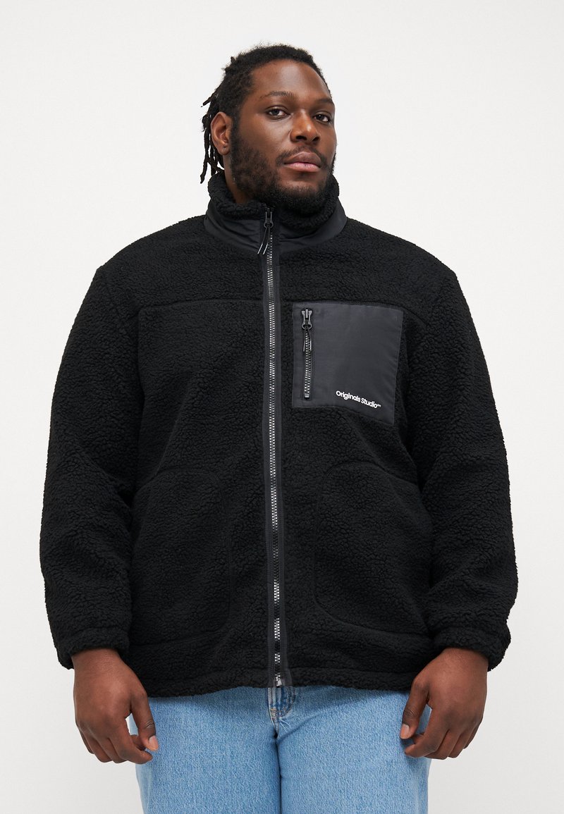 Μαύρη φλις ζακέτα με ψηλό γιακά, φερμουάρ μπροστά και τσέπη στο στήθος. Διαθέτει υφή υφάσματος και αντίθετο υλικό τσέπης μαύρου χρώματος.