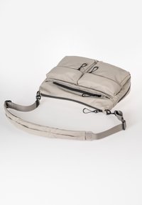Borsa a spalla imbottita grigia con due tasche esterne con zip, tracolla regolabile e tessuto resistente. Presenta toggle e dettagli di cucitura.
