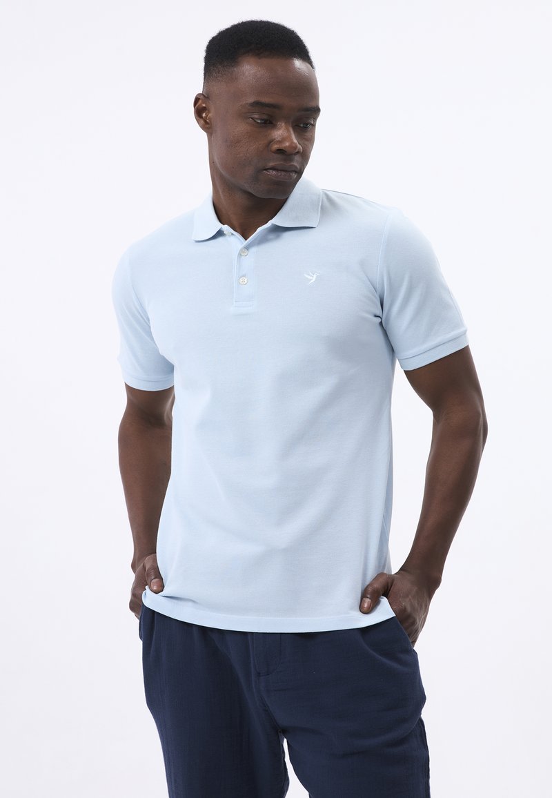 Helles blaues Poloshirt aus strukturiertem Stoff, mit Kragen, kurzen Ärmeln und einem dezenten Logo auf der linken Brust.