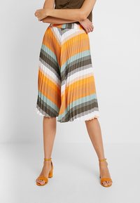 Falda plisada hasta la rodilla con rayas en zigzag en naranja, verde azulado, marrón y blanco. Tela ligera con cinturilla elástica.